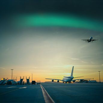 Airplane on tarmac, aurora borealis in the sky above