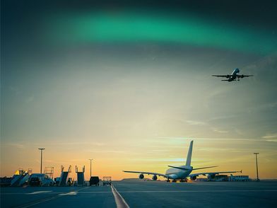 Airplane on tarmac, aurora borealis in the sky above