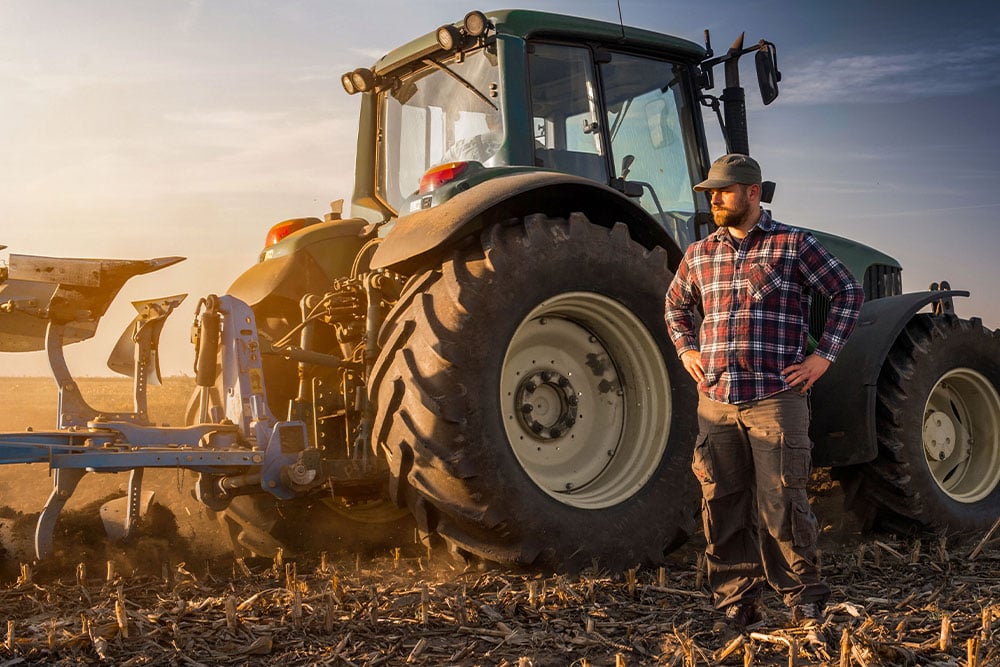 Landwirt vor modernem Traktor auf dem Feld mit AdBlue und Emissionsvorgaben