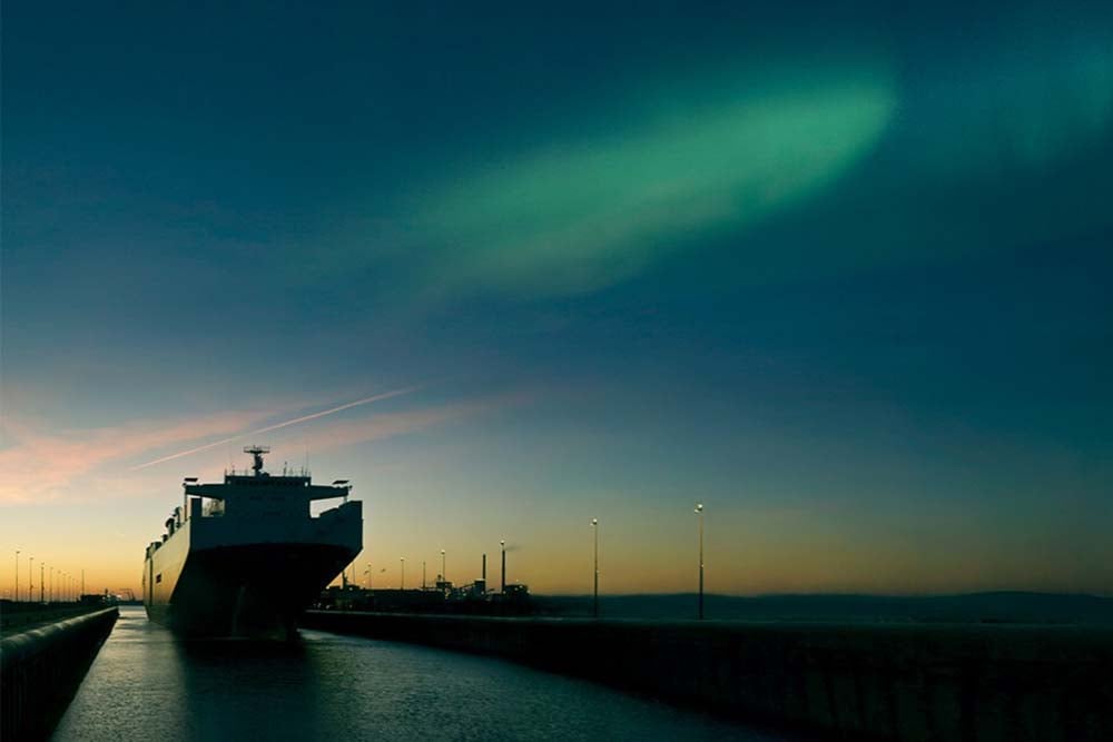 Containerschiff unter Polarlichtern symbolisiert alternative Schiffskraftstoffe und nachhaltige Flottenplanung