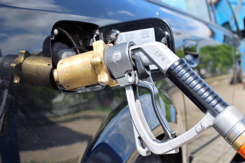 Mitarbeiterin im Tankstellenshop bietet Autogas-Zapfpistolen und Zubehör an