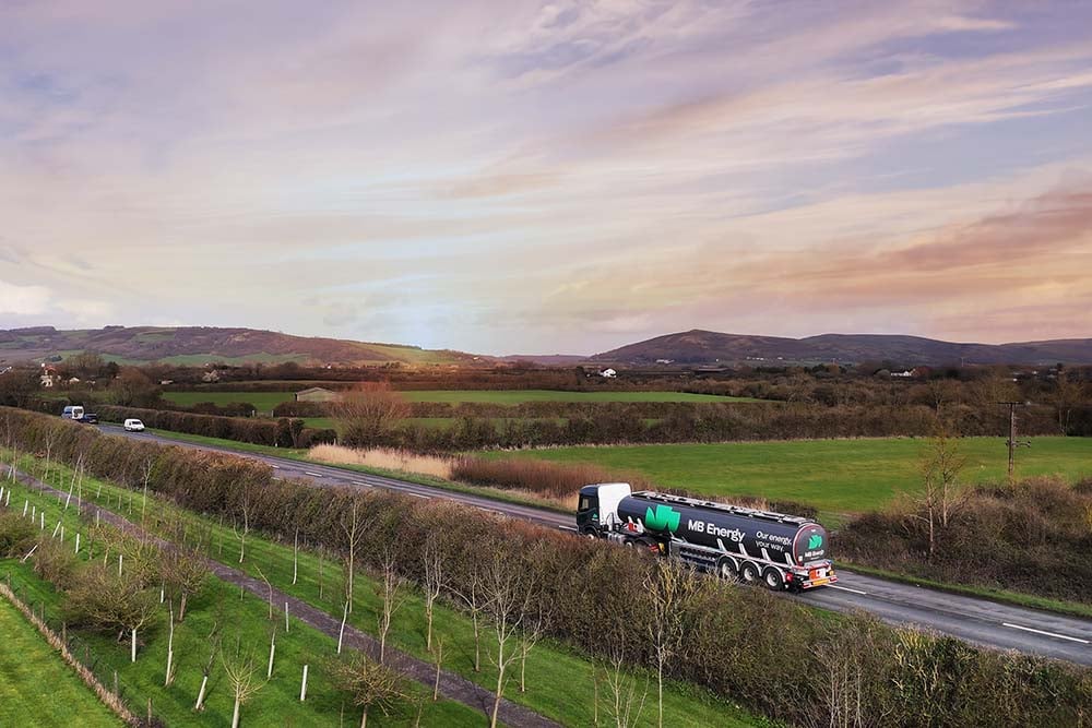 UK truck driving through rural fields under a clear sky