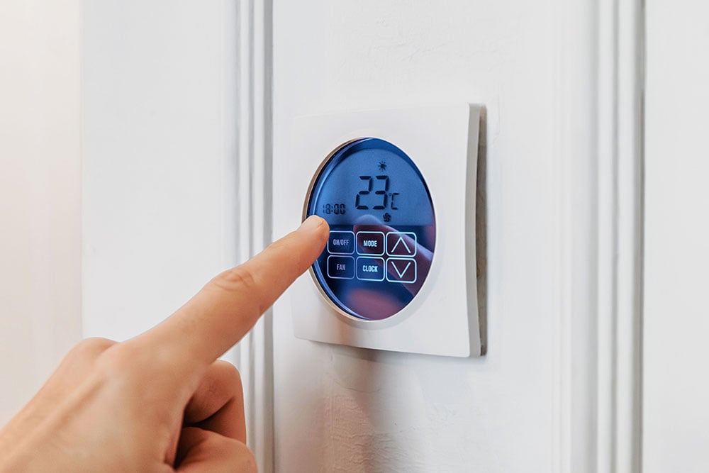 Finger adjusts wall thermostat for efficient heat control in a single-family home 