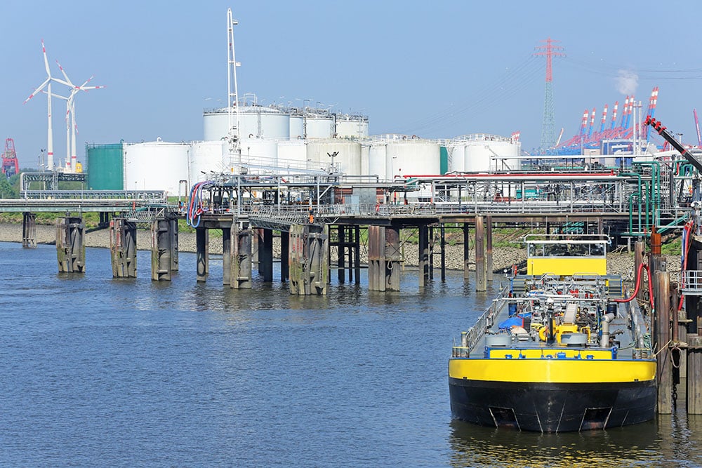 Tank storage facility with pipelines and barge handling HVO fuel transfer at an industrial port terminal