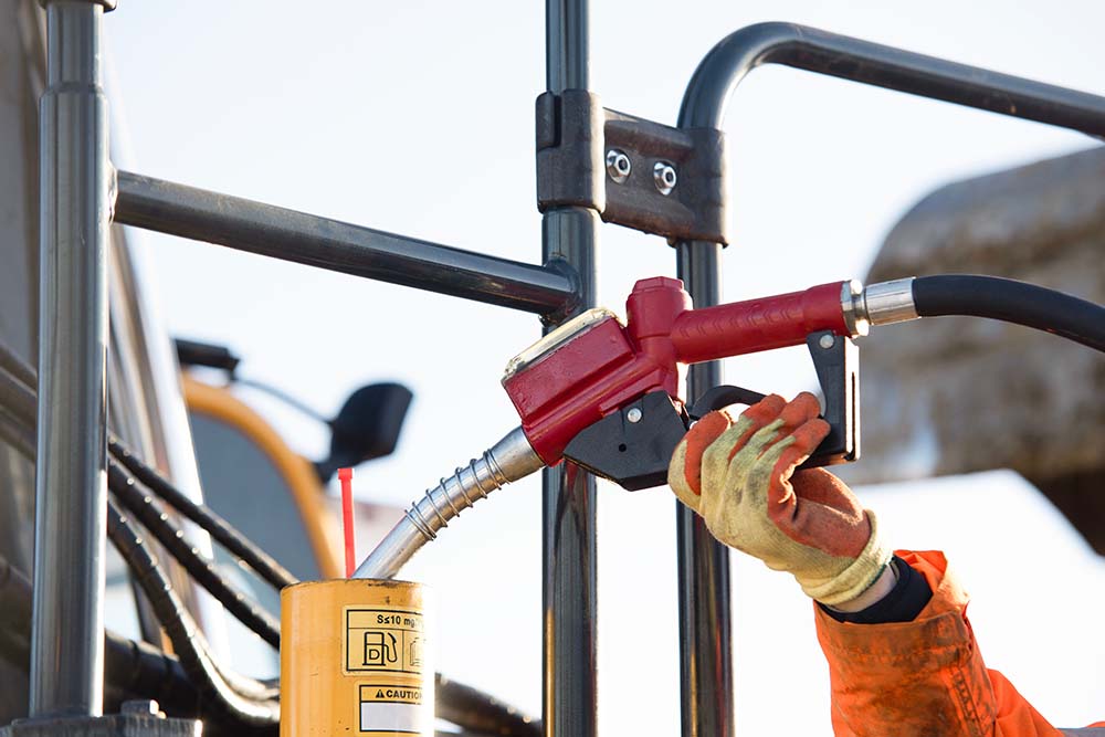 Arbeiter betankt schwere Baumaschine mit Diesel auf Baustelle